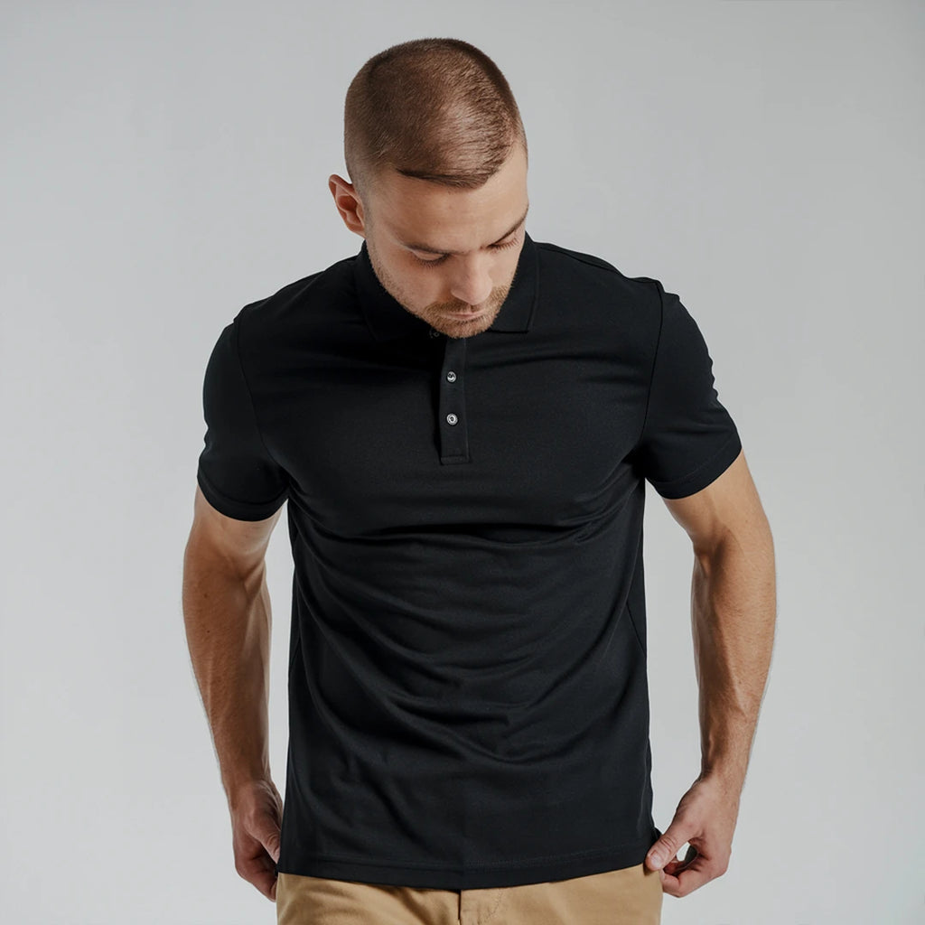 A man wearing a black French Polo T-Shirt with short sleeves, a collar, and button-up neck.