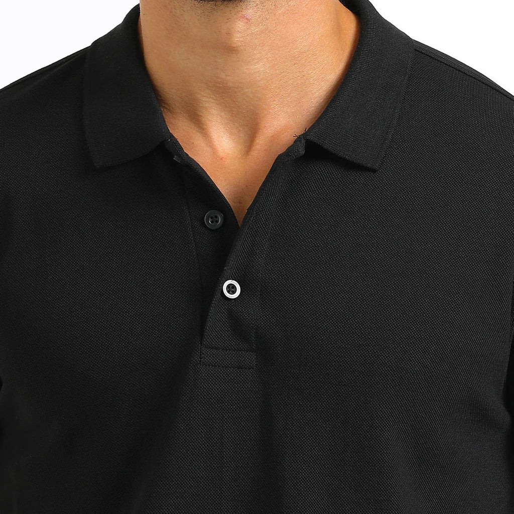 A man wearing a black French Polo T-Shirt with short sleeves, a collar, and button-up neck.