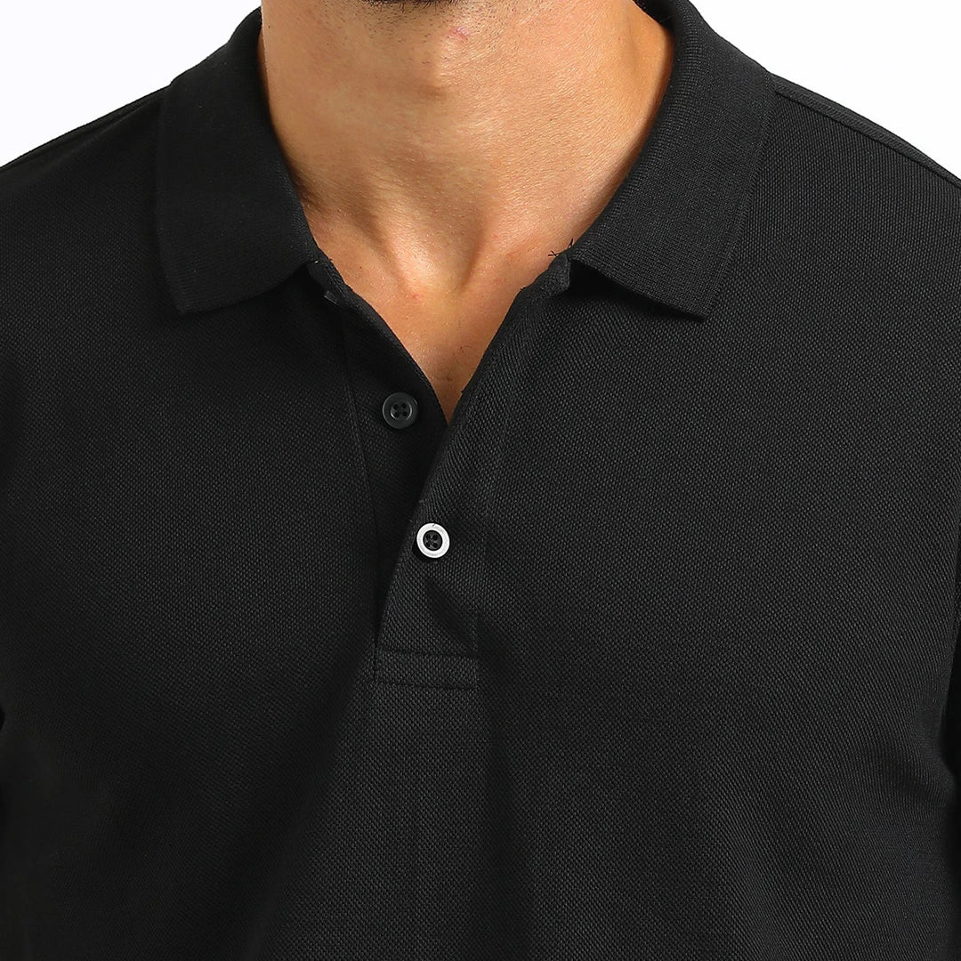 A man wearing a black French Polo T-Shirt with short sleeves, a collar, and button-up neck.