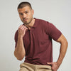 A man wearing a maroon French Polo T-Shirt with short sleeves, a collar, and button-up neck.
