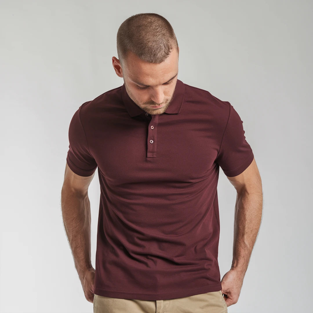 A man wearing a maroon French Polo T-Shirt with short sleeves, a collar, and button-up neck.