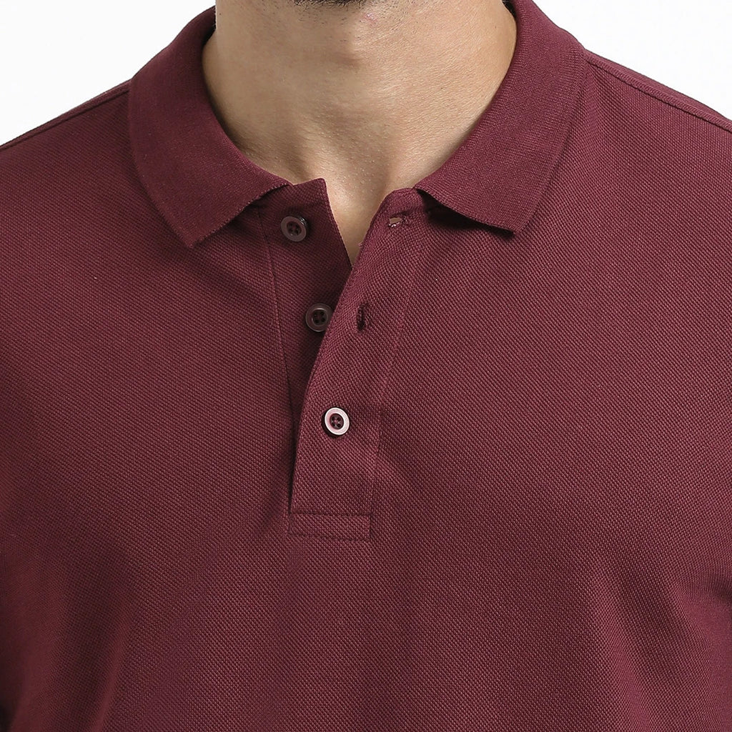 A man wearing a maroon French Polo T-Shirt with short sleeves, a collar, and button-up neck.
