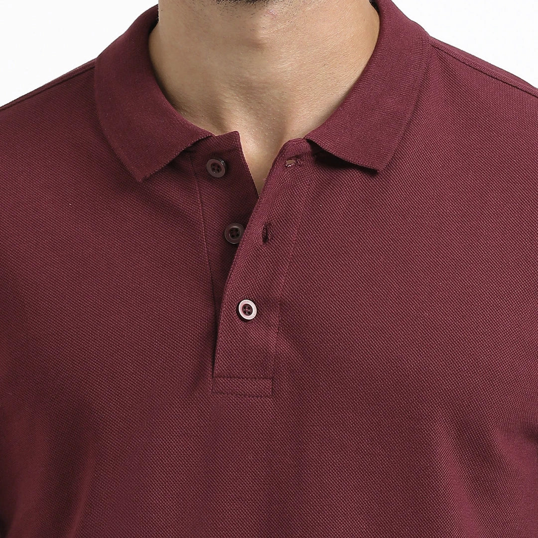 A man wearing a maroon French Polo T-Shirt with short sleeves, a collar, and button-up neck.