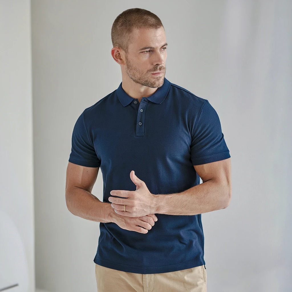 A man wearing a navy French Polo T-Shirt with short sleeves, a collar, and button-up neck.