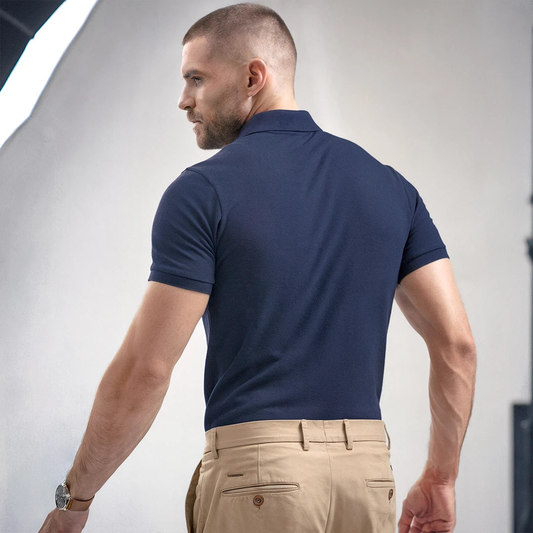 A man wearing a navy French Polo T-Shirt with short sleeves, a collar, and button-up neck.