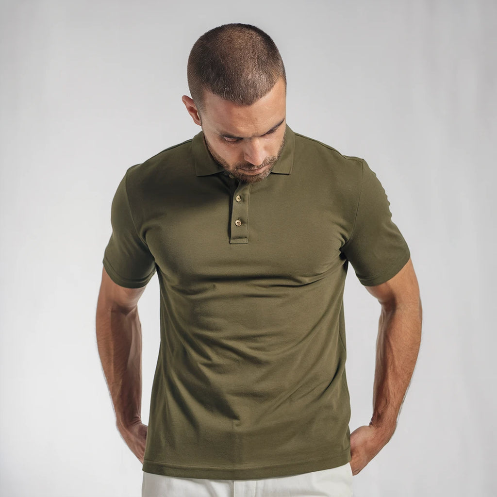 A man wearing a olive green French Polo T-Shirt with short sleeves, a collar, and button-up neck.