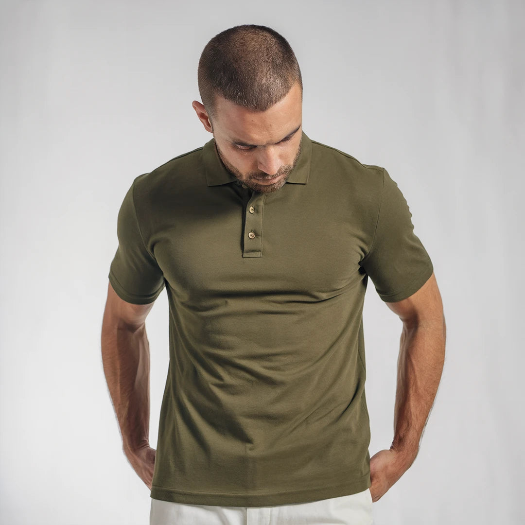 A man wearing a olive green French Polo T-Shirt with short sleeves, a collar, and button-up neck.