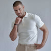 A man wearing a white French Polo T-Shirt with short sleeves, a collar, and button-up neck.