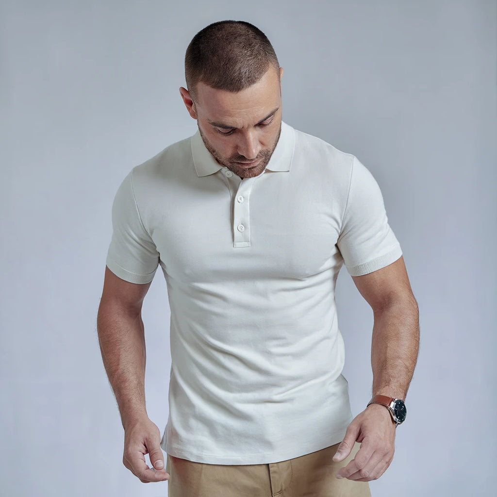 A man wearing a white French Polo T-Shirt with short sleeves, a collar, and button-up neck.
