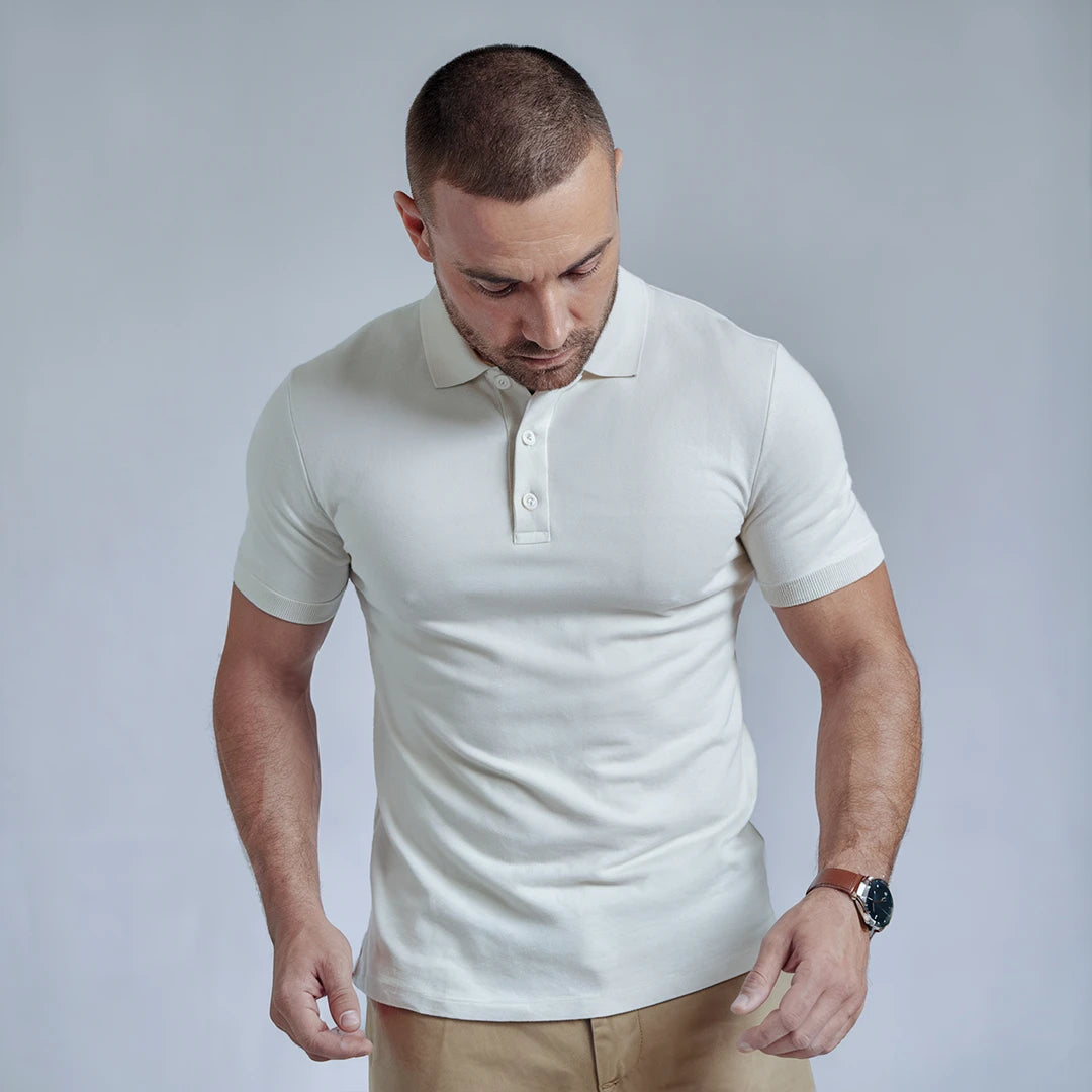 A man wearing a white French Polo T-Shirt with short sleeves, a collar, and button-up neck.