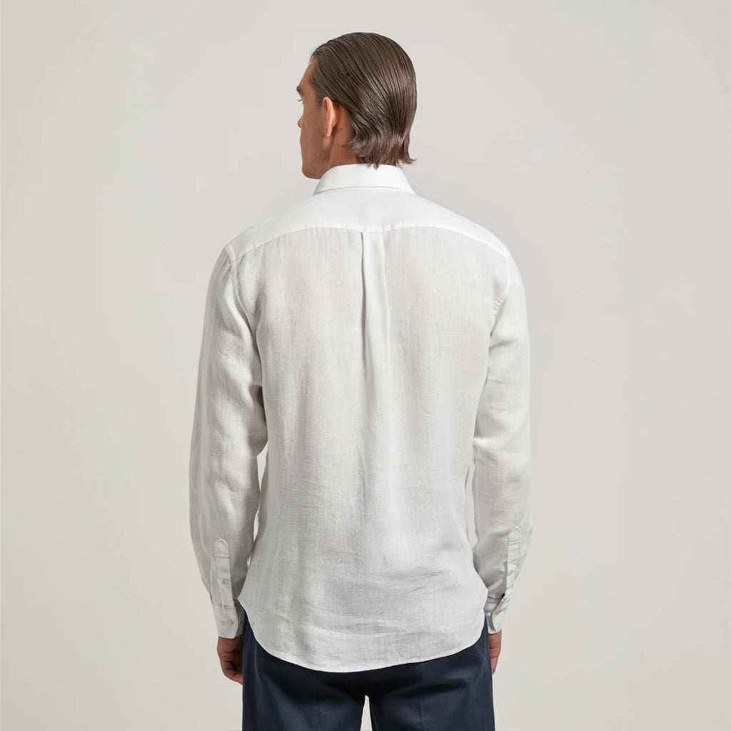 A man wearing a white linen shirt with a classic spread collar and mother-of-pearl buttons, paired with dark trousers.