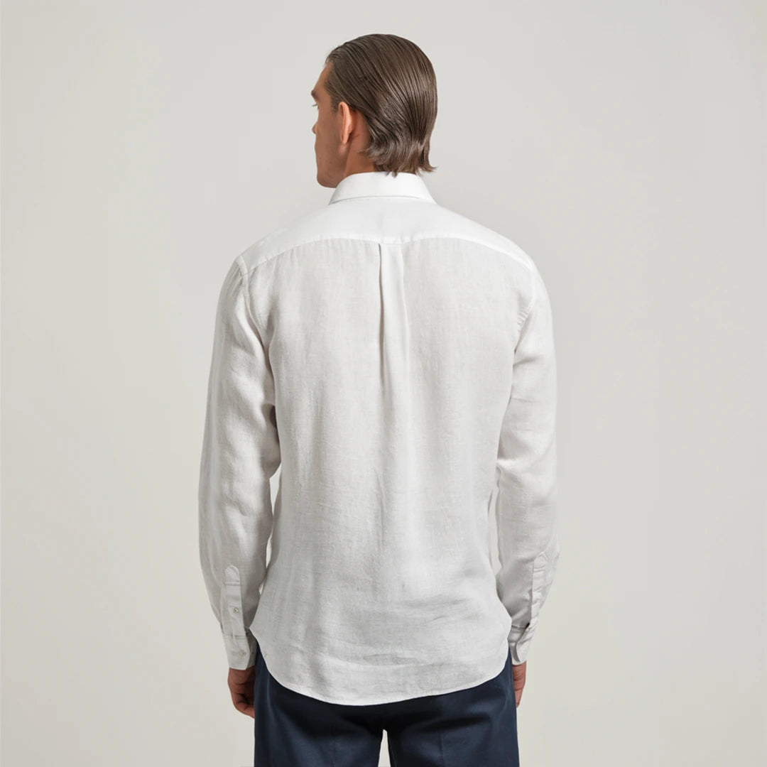 A man wearing a white linen shirt with a classic spread collar and mother-of-pearl buttons, paired with dark trousers.
